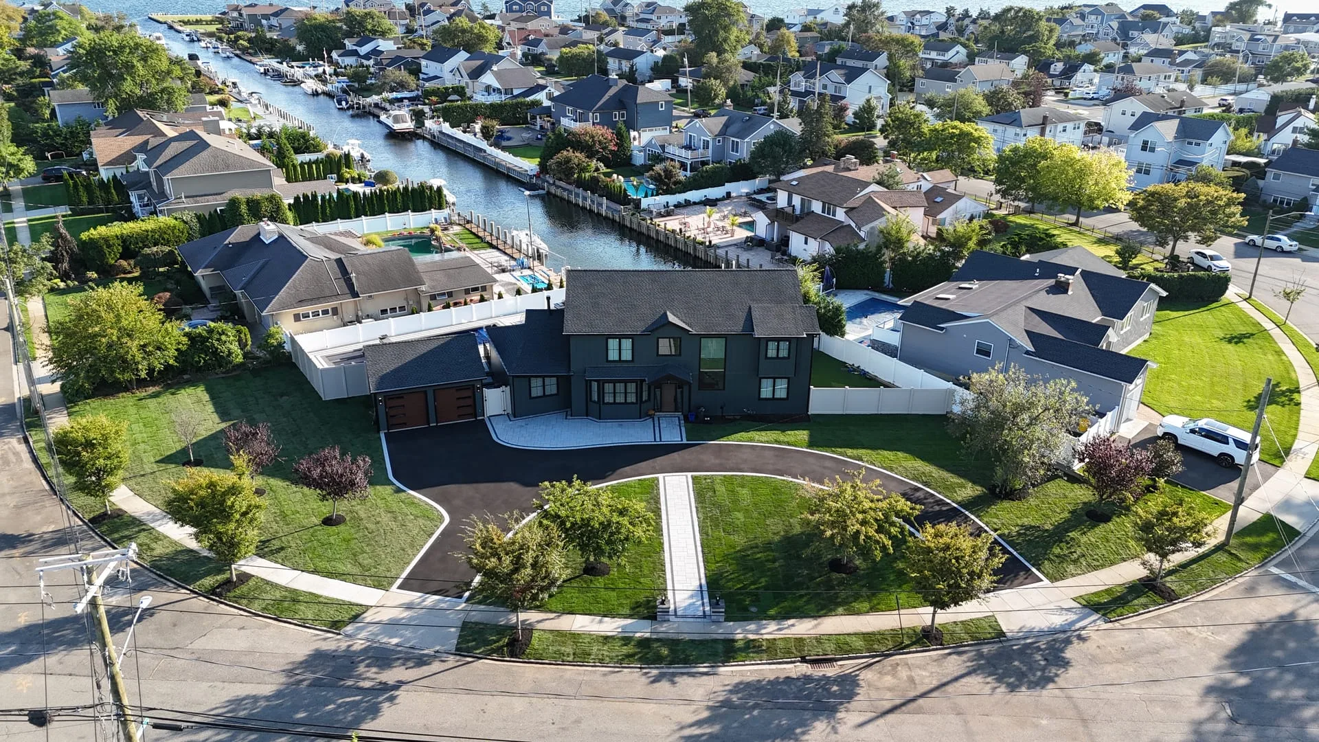 After: curved asphalt driveway with walkway and full landscaping at Massapequa waterfront by Brothers Paving